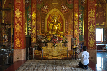 Fototapeta na wymiar Praying man in front of a statue of Buddha in the temple