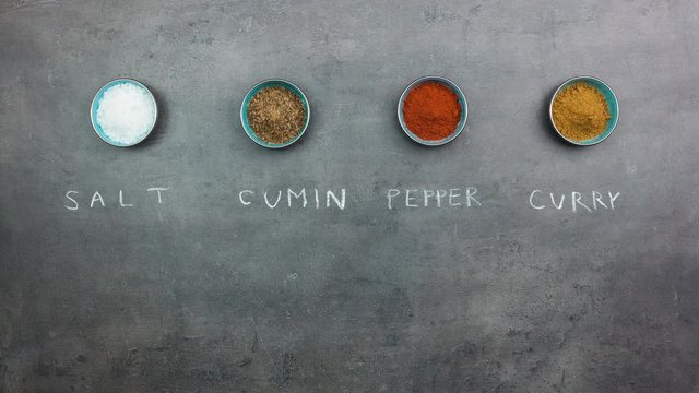 Top view on salt and spices in bowls on grey kitchen counter. Stop motion animation.