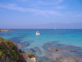Turquoise and limpid sea with boats on the coast of Upper Corsica, France