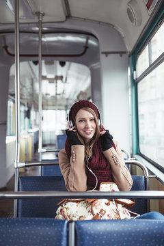 Beautiful young woman sitting in tram and listening to music.