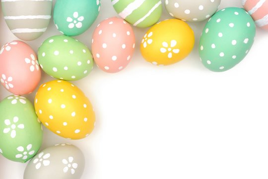 Corner border of hand painted pastel Easter eggs over a white background
