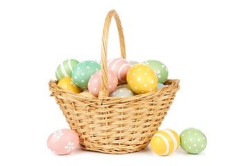 Naklejka premium Easter basket filled with hand painted pastel Easter Eggs over a white background