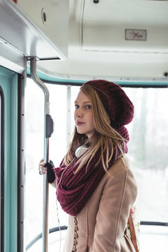 Beautiful young woman standing in tram and looking through window. 