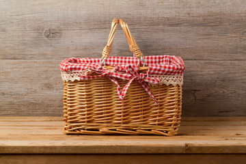 Picnic basket with checked cloth on table over wooden wall background