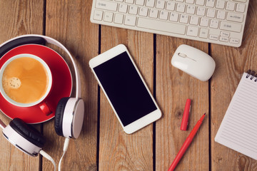 Office table with smartphone, headphones and coffee cup. Business workplace or workspace concept. Top view from above