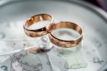 macro of wedding rings next to the flowers and romantic clock