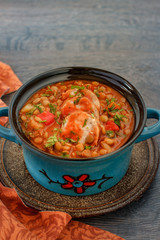 Italian lentil stew with bolognese sauce and sausage in a bowl with parsley on rustic wooden table