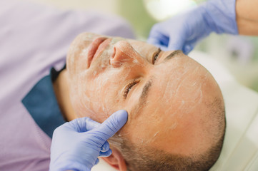 Obraz na płótnie Canvas Relaxed man having a face massage and a peeling treatment