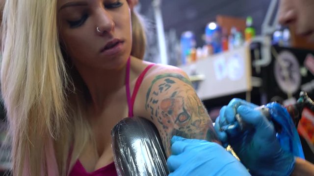 Sexy blonde and tattoo master at work in studio