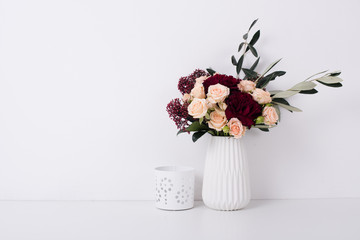 roses and carnations in a vase in white interior