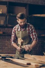 concenrated handsome cabinetmaker work with chisel and hammer. Stylish craftsman with brutal...