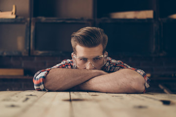 Closeup photo of serious handsome joiner look at camera near tabletop with tools.  Stylish young...