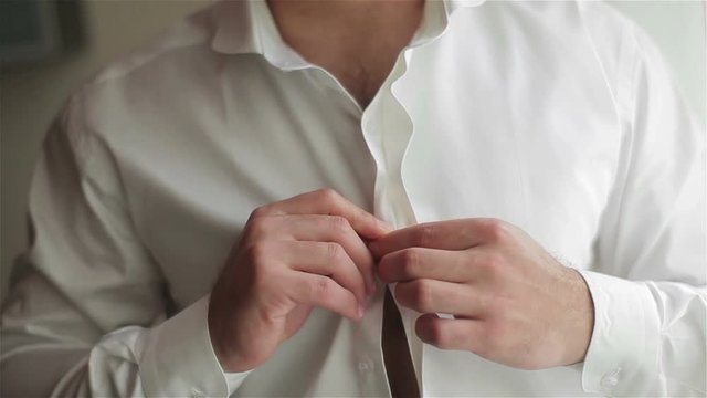Man dressing close-up shallow dof. Male hands buttoning white shirt fast. Man with beard dressing wear clothes for going to work in the morning. Body chest hair and masculinity macho