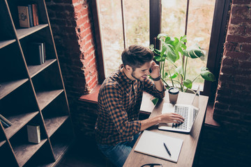Top view of young student working on laptop and talking on phone