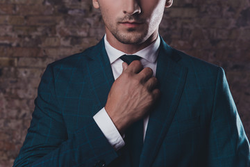 Close up of stylish man in black suit correcting tie