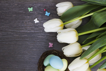 Fototapeta na wymiar Bouquet white tulip flowers with easter eggs on wooden table. Place for your text. Easter background. 