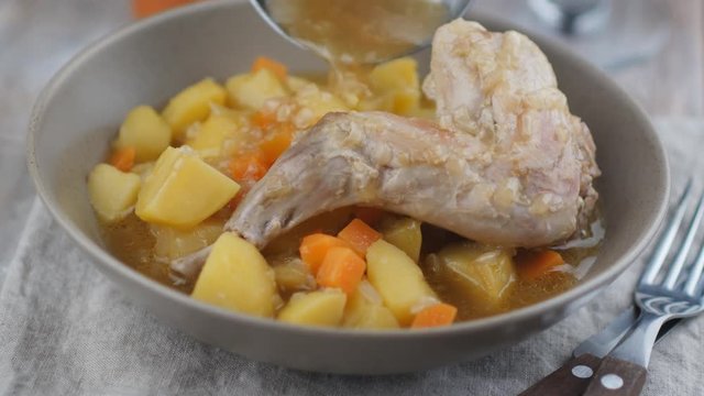 Adding gravy to the braised rabbit leg with potato and carrot