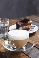Cappuccino and cake on the wooden table.