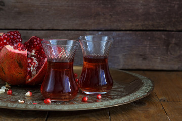 A glasses of pomegranate juice with fresh pomegranate fruits on wooden table. Vitamins and minerals. Healthy drink concept.