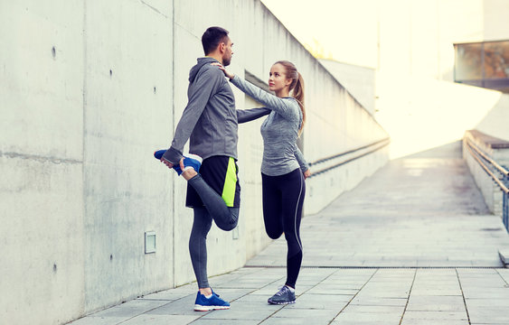 smiling couple stretching leg outdoors