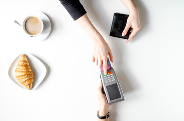Croissant and coffee payment by card in cafe top view
