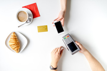 Coffee, croissant and card payment on white background top view