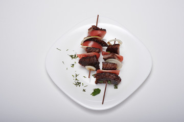shish kebab on a plate on a white background