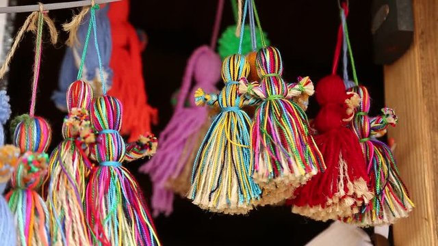Dolls of women made of threads in souvenir shop. Colorful dolls hanging on strings
