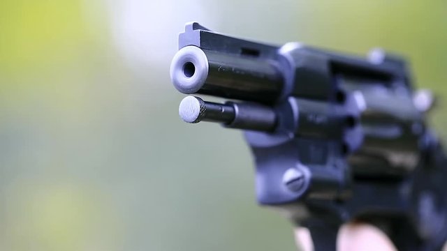 Black revolver close-up. Man holds in hand black revolver. Shots from a black pistol. Man with black gun, close up