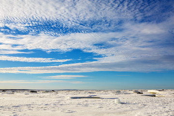 Beautiful panorama of the North sea frozen in the ice. Nature water icy in the winter. Landscape snowy expanse to the horizon with a wonderful sky and clouds.