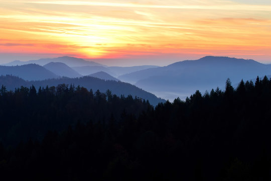 Sunrise in Slovakia. Orange sun sky over dark mountains. Romantic atmosphere. Fog hills at sunset.