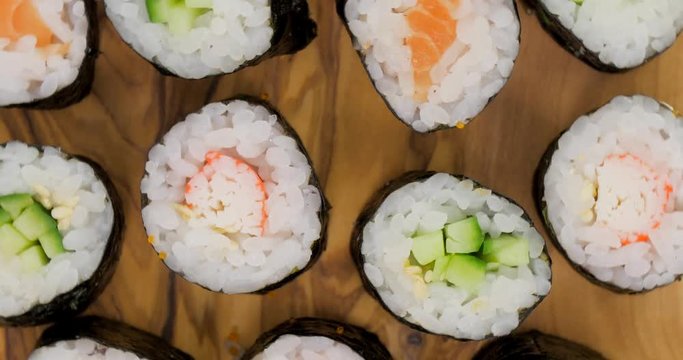 Collection of japanese sushi maki rolls rotating on a wooden surface
