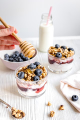 Cooking breakfast with granola and berries on white kitchen background