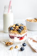 Homemade fitness granola with yoghurt and berries on white kitchen background