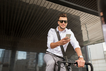Fototapeta na wymiar man with bicycle and smartphone on city street