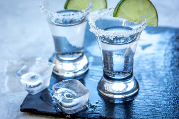 Silver tequila shots with lime and salt on gray stone background