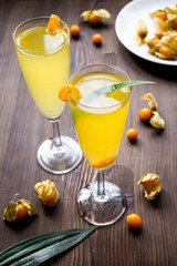 cocktail with physalis in glass on wooden background