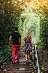 Loving couple in a tunnel of green trees on railroad