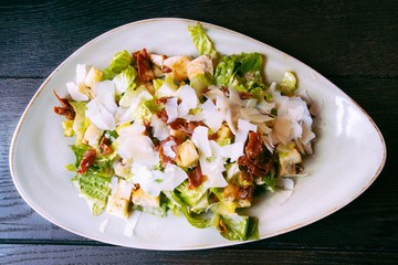 Caesar salad in a plate on dark wooden background