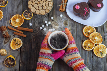 cup of black hot coffee in her hands, wearing colorful winter gloves on hands