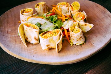 Tortilla wraps with rice and vegetables on wooden plate