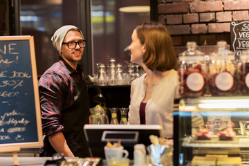 happy bartenders at cafe or coffee shop counter