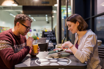 happy couple with tablet pc and smoothie at cafe