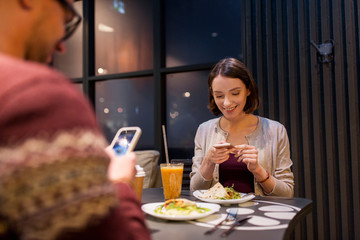 happy couple with smartphones at vegan restaurant