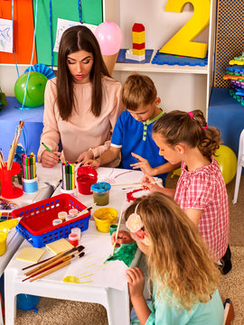 Children painting and drawing in kids club. Craft lesson in primary school. Kindergarten teacher and small students work together. Girl paints felt-tip pen. Kid boy and girl coloring picture in class.