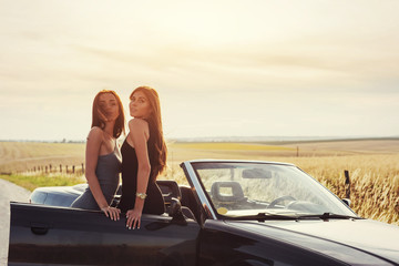 Two sexy brunette woman standing near her car
