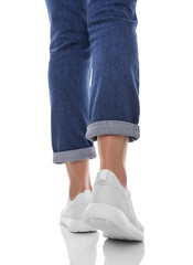 Women's legs in jeans and sneakers.