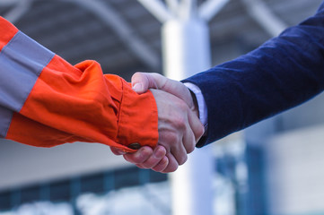 businessman handshaking with worker. Handshake of suit and boilersuit. Business modern background
