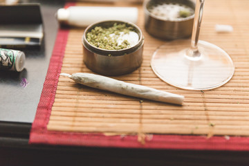 Obraz na płótnie Canvas Joint, grinder, cannabis buds, and related items on a table.