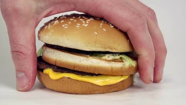 Large male hand picks up a junk food burger